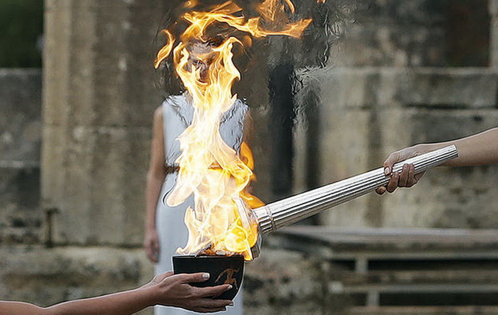 Actress Katerina Lehou, right, as high priestess, lights the torch during the lighting ceremony of the Olympic flame in Ancient Olympia, southwestern Greece, on Tuesday, Oct. 24, 2017. The flame will be transported by torch relay to Pyeongchang, South Korea, which will host the Feb. 9-25, 2018 Winter Olympics. (AP Photo/Thanassis Stavrakis)