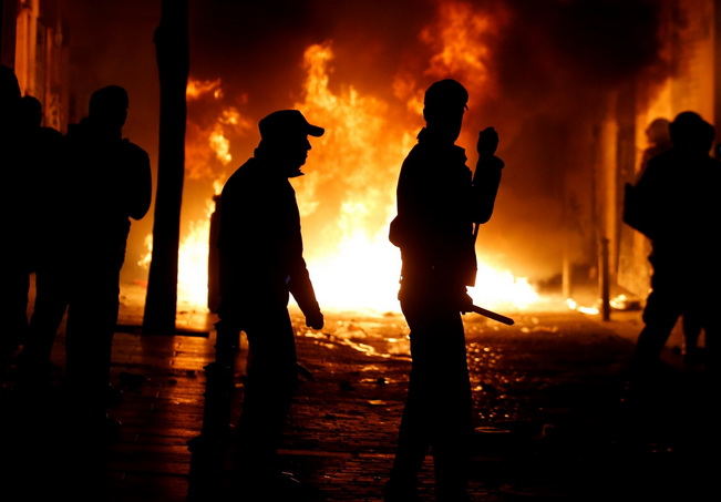 Spanish National police officers stand in front of burning garbage bins during clashes after a street hawker died in central Madrid, Spain, March 15, 2018. REUTERS/Stringer NO RESALES. NO ARCHIVE.